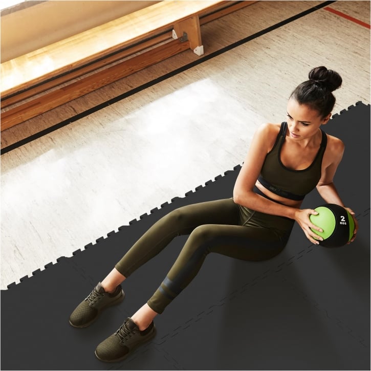 Kvinna som tränar med en träningsboll på gymgolv från gorilla sports